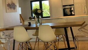A modern kitchen with a wooden island, white chairs, and a vase of flowers. - Villa Familiale Centre Bourg sur 2500m² Paysager (Sallebœuf)