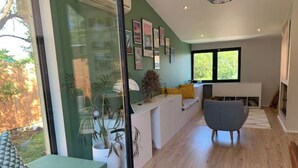 A modern living room with a large window, a sofa, a chair, and a fireplace. - Villa Familiale Centre Bourg sur 2500m² Paysager (Sallebœuf)