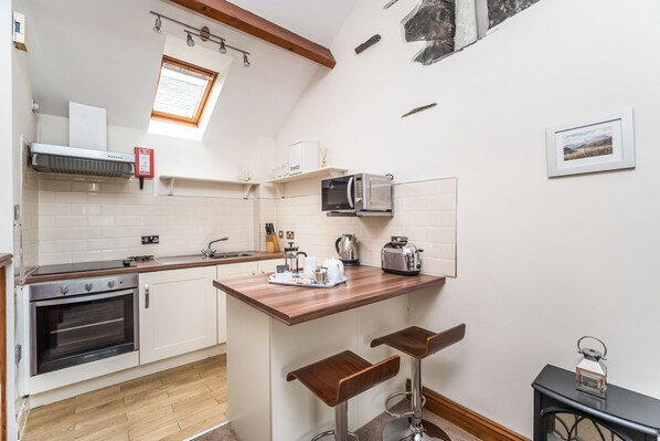 A compact kitchen with a built-in oven, microwave, and a small bar area with stools.