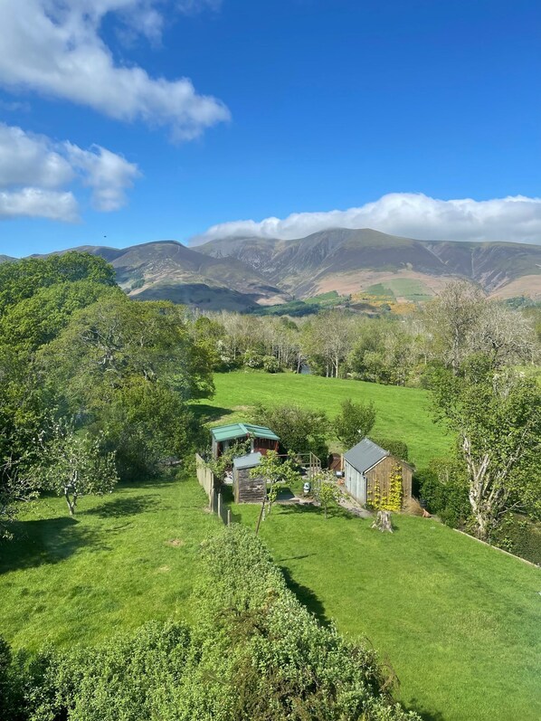 A rural landscape with a small house surrounded by green fields and hills.