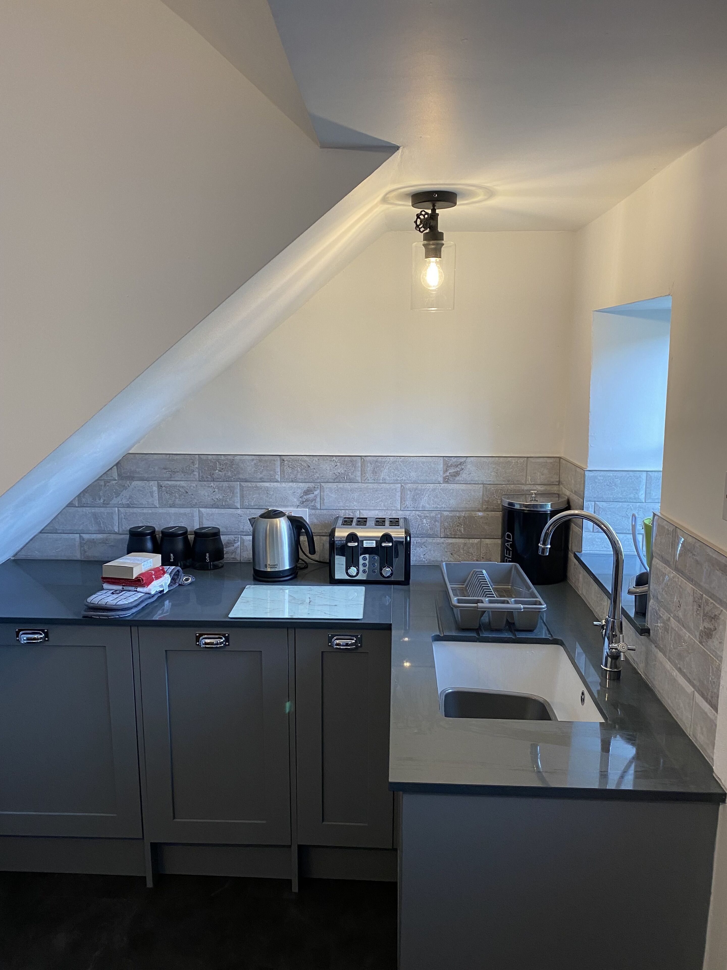A modern kitchen with a built-in oven, a coffee maker, a toaster, and a kettle on the counter.