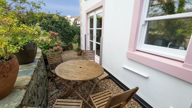 A patio with a round wooden table and chairs, surrounded by potted plants and a stone wall. - Greta Bank -  an apartment that sleeps 4 guests  in 2 bedrooms (Central Keswick)