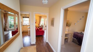 A hallway leading to a bedroom with a bed, a red sofa, and a dining area with a table and chairs. - Greta Bank -  an apartment that sleeps 4 guests  in 2 bedrooms (Central Keswick)