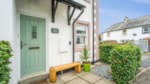 Un edificio pintoresco con una puerta verde, un banco y un letrero que dice "Maiden Moor".