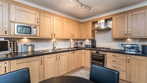 Una cocina moderna con armarios de madera, electrodomésticos de acero inoxidable y una encimera negra.