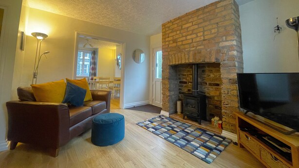 A living room with a fireplace, a sofa, a television, and a patterned rug. - Byways -  a cottage that sleeps 4 guests  in 2 bedrooms (Central Keswick)
