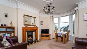 Una sala de estar con chimenea, televisor, mesa de comedor con sillas y un ventanal con vistas.