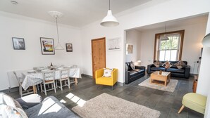 A modern living room with a dining area, featuring a sofa, a yellow armchair, and a coffee table. - Coleridge Cottage -  a cottage that sleeps 5 guests  in 3 bedrooms (Central Keswick)