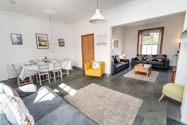 Una sala de estar moderna con comedor, que incluye un sofá, un sillón amarillo y una mesa de centro.