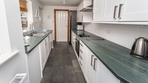 A narrow kitchen with white cabinets, a green countertop, and a microwave. - Coleridge Cottage -  a cottage that sleeps 5 guests  in 3 bedrooms (Central Keswick)