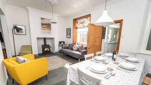 A modern living room with a yellow sofa, a fireplace, and a dining area set for a meal. - Coleridge Cottage -  a cottage that sleeps 5 guests  in 3 bedrooms (Central Keswick)