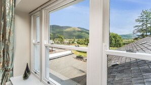 Een kamer met een groot raam met uitzicht op een schilderachtig landschap, met bergen en een heldere lucht.