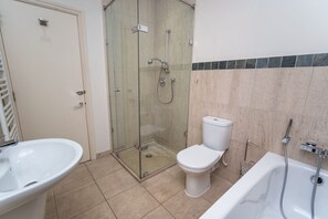 A bathroom with a glass-enclosed shower, a toilet, a sink, and a bathtub.