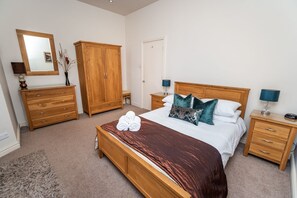 A bedroom with a wooden bed, a wooden wardrobe, a dresser, and a nightstand with a lamp. - Crandy Nook -  a maisonette that sleeps 6 guests  in 4 bedrooms (Central Keswick)