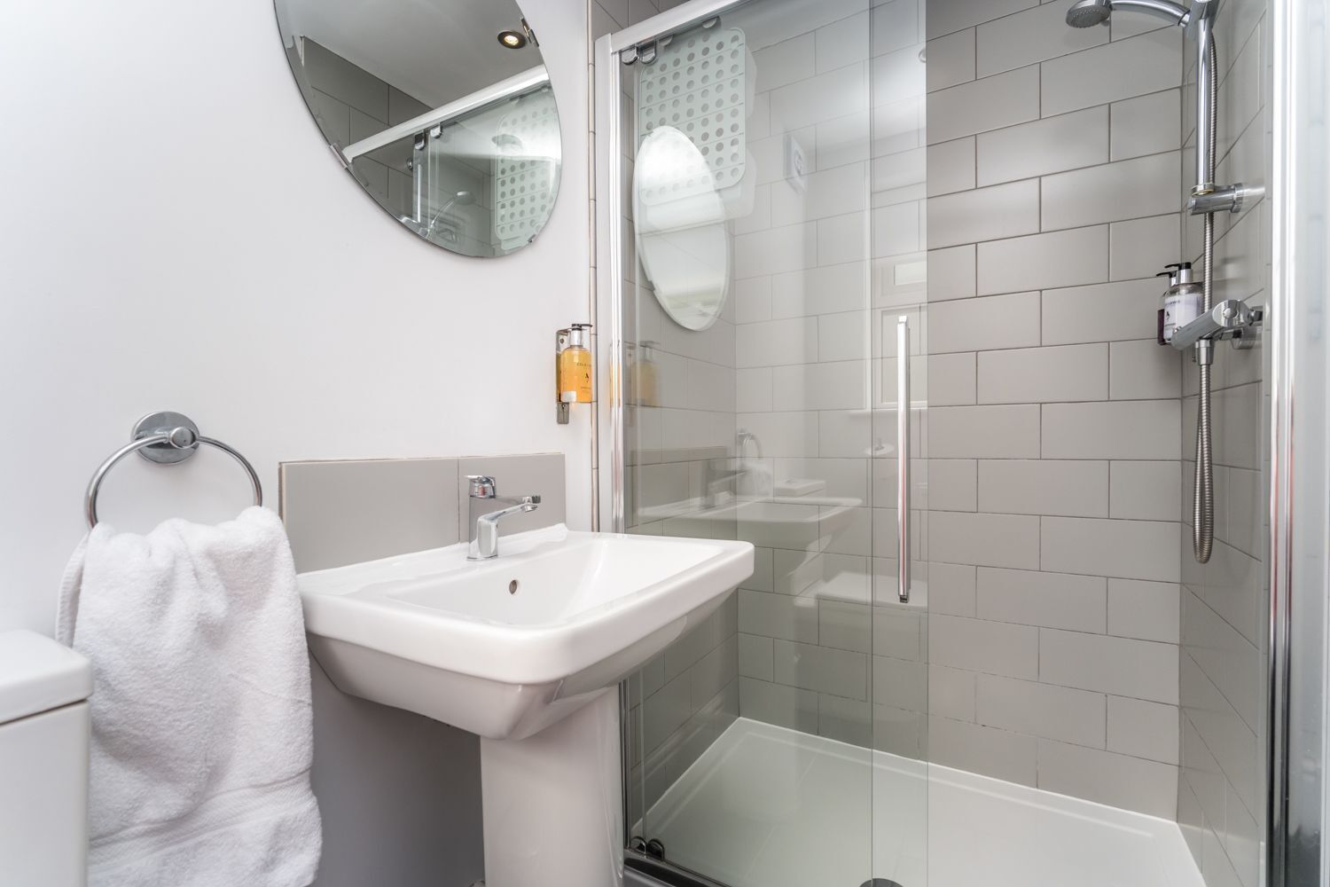 Ein modernes Badezimmer mit Waschbecken, Spiegel, Toilette und Duschkabine.