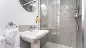 Ein modernes Badezimmer mit Waschbecken, Spiegel, Toilette und Duschkabine.