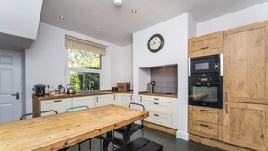 Eine moderne Küche mit Holztisch, weißen Schränken und einem schwarzen Ofen.
