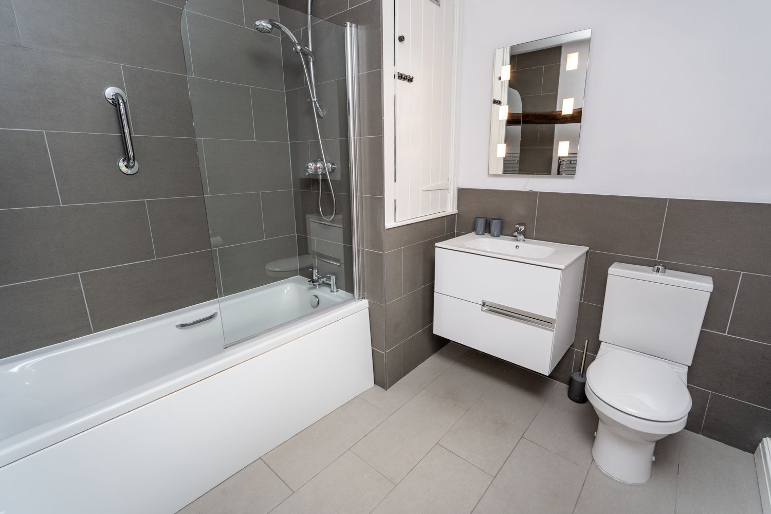 Une salle de bain moderne avec une baignoire, des toilettes et un meuble-lavabo avec un miroir.