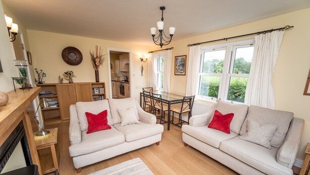 A cozy living room with two sofas, a dining table, and a kitchen in the background. - 11 Howrah's Court -  an apartment that sleeps 4 guests  in 2 bedrooms (Central Keswick)