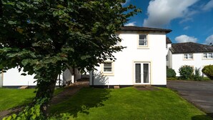 A two-story white house with a front door, a small porch, and a well-maintained lawn.