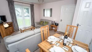 A compact living space with a sofa set, a dining table set for four, and a television in the corner.