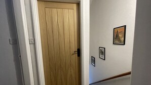 Ein Flur mit einer Holztür, einer Treppe und gerahmten Bildern an der Wand.