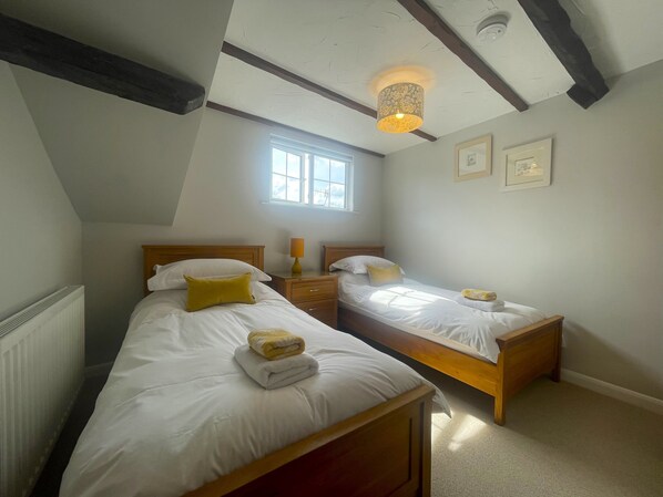Un dormitorio con dos camas individuales, una ventana, una lámpara en el techo y un radiador.