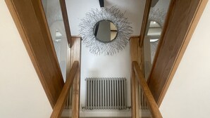 A wooden staircase with a radiator and a decorative mirror at the top. - Daisy Cottage -  a cottage that sleeps 4 guests  in 2 bedrooms (Central Keswick)