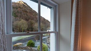 Una habitación con un ventanal que ofrece vistas a un paisaje rural con una colina y árboles.