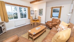 Una sala de estar acogedora con una mesa de centro de madera, un sofá de cuero y un comedor con mesa y sillas.