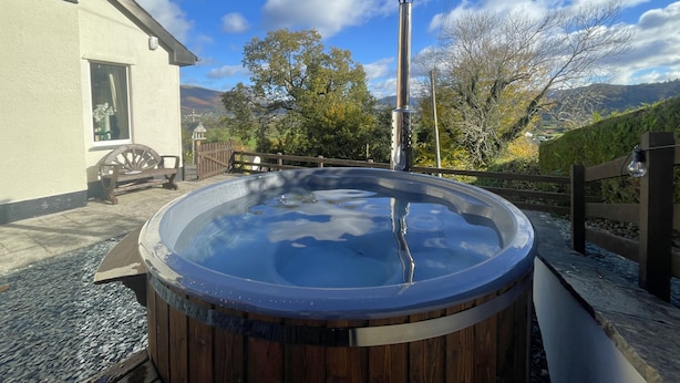 Un jacuzzi con revestimiento de madera, una barra de metal y una valla de madera.
