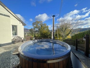 A hot tub with a wooden exterior, a metal pole, and a wooden fence. - Rock Lynn -  a bungalow that sleeps 4 guests  in 2 bedrooms (Braithwaite)