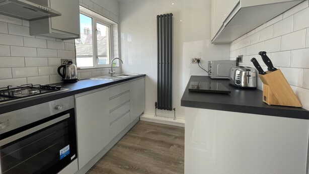 Een compacte keuken met een gasfornuis, oven en een magnetron. Er is een raam dat natuurlijk licht en uitzicht biedt.