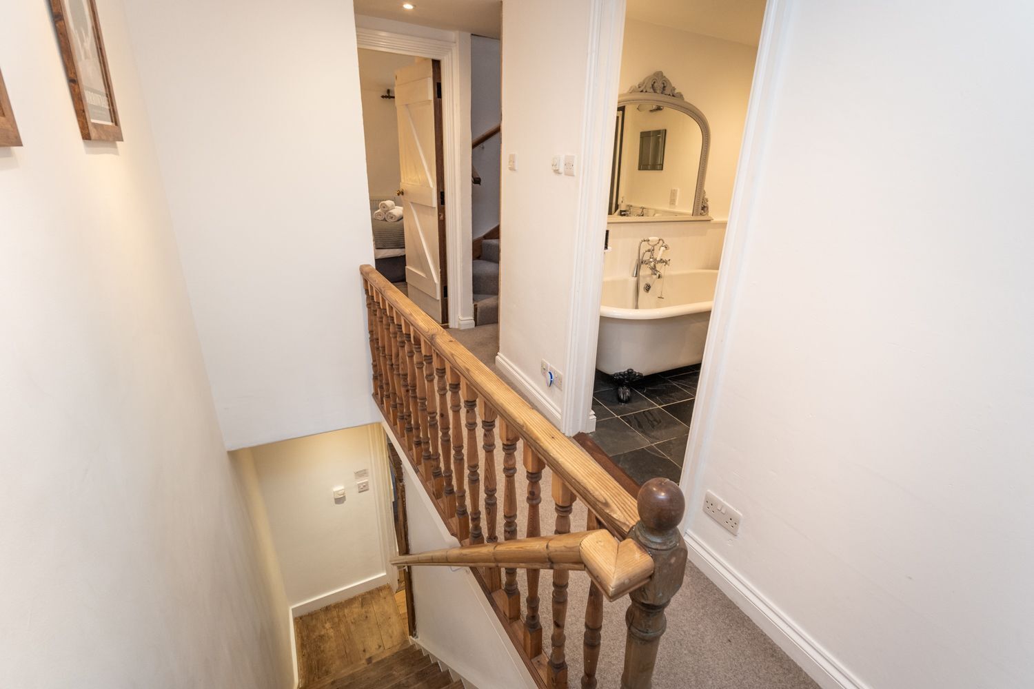 A staircase leading to a bathroom with a bathtub and a mirror.