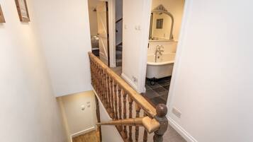 A staircase leading to a bathroom with a bathtub and a mirror.
