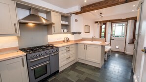 A modern kitchen with grey cabinets, a stainless steel range hood, a built-in oven, and a sink. - Barf Cottage -  a cottage that sleeps 5 guests  in 3 bedrooms (Portinscale)