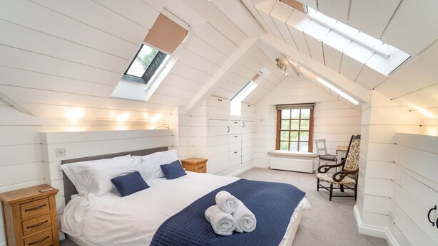 A bedroom with a bed, bedside tables, a chair, a window, and a skylight. - Barf Cottage -  a cottage that sleeps 5 guests  in 3 bedrooms (Portinscale)