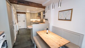 A compact kitchen with a wooden table, a washing machine, and a map on the wall. - Barf Cottage -  a cottage that sleeps 5 guests  in 3 bedrooms (Portinscale)
