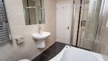 Un baño moderno con una bañera blanca, un lavabo, una cabina de ducha de vidrio y una puerta.