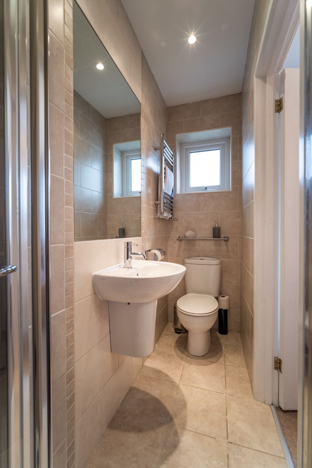 A compact bathroom with a sink, toilet, and a small window.