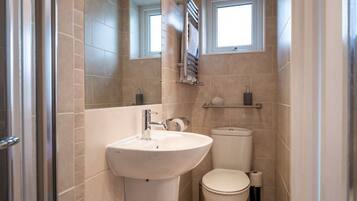 A compact bathroom with a sink, toilet, and a small window.