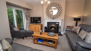 A living room with a fireplace, a television, and a sofa. - Appletree -  a house that sleeps 6 guests  in 3 bedrooms (Portinscale)