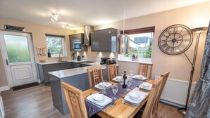 A modern kitchen with a central island, dining table set for six, and a large window with a view. - Appletree -  a house that sleeps 6 guests  in 3 bedrooms (Portinscale)
