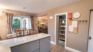 A modern kitchen with a central island, wooden chairs, and a dining table set for four. - Appletree -  a house that sleeps 6 guests  in 3 bedrooms (Portinscale)
