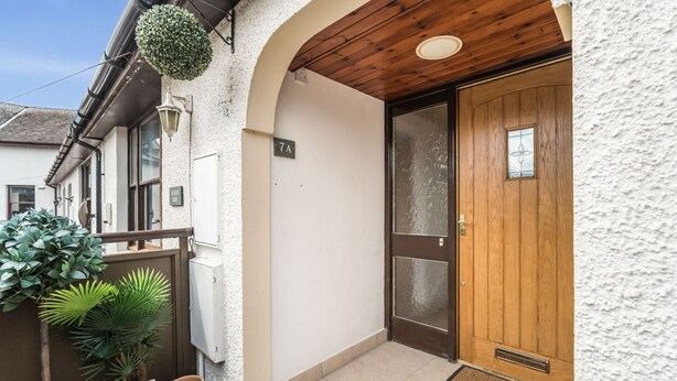 A residential building with a wooden door, a small porch area, and a potted plant. - Alban Rise -  a maisonette that sleeps 5 guests  in 3 bedrooms (Central Keswick)
