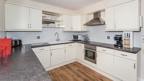 A modern kitchen with white cabinets, a stainless steel oven, a microwave, and a coffee maker. - Alban Rise -  a maisonette that sleeps 5 guests  in 3 bedrooms (Central Keswick)