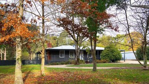 Ein zweistöckiges Haus mit Veranda, umgeben von Bäumen mit Herbstlaub.