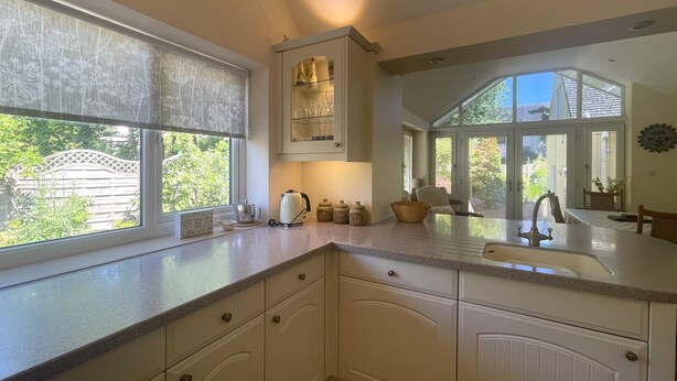 A kitchen with white cabinets, a built-in oven, and a window with a view of greenery.
