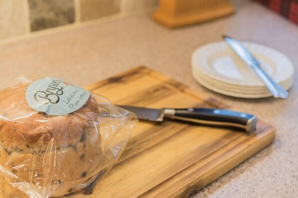 A loaf of bread on a wooden cutting board with a knife beside it.