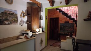 A kitchen with a wooden cabinet, a sink, and a countertop. There is a staircase leading to another room.